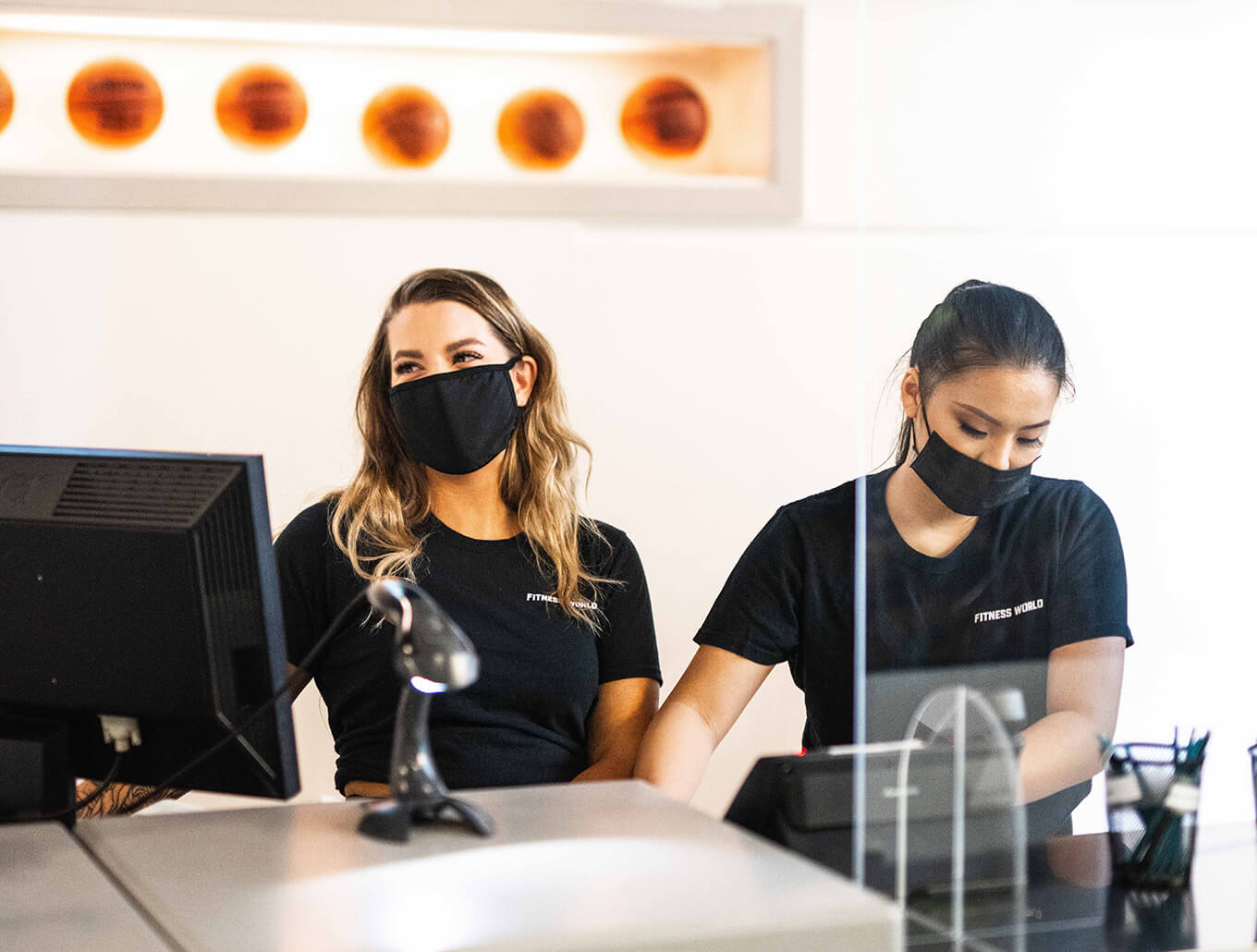 two female masked fitness world employees
